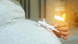 Schwanger Frau stellt ein Spielzeug-Flugzeug auf ihrem Bauch ab