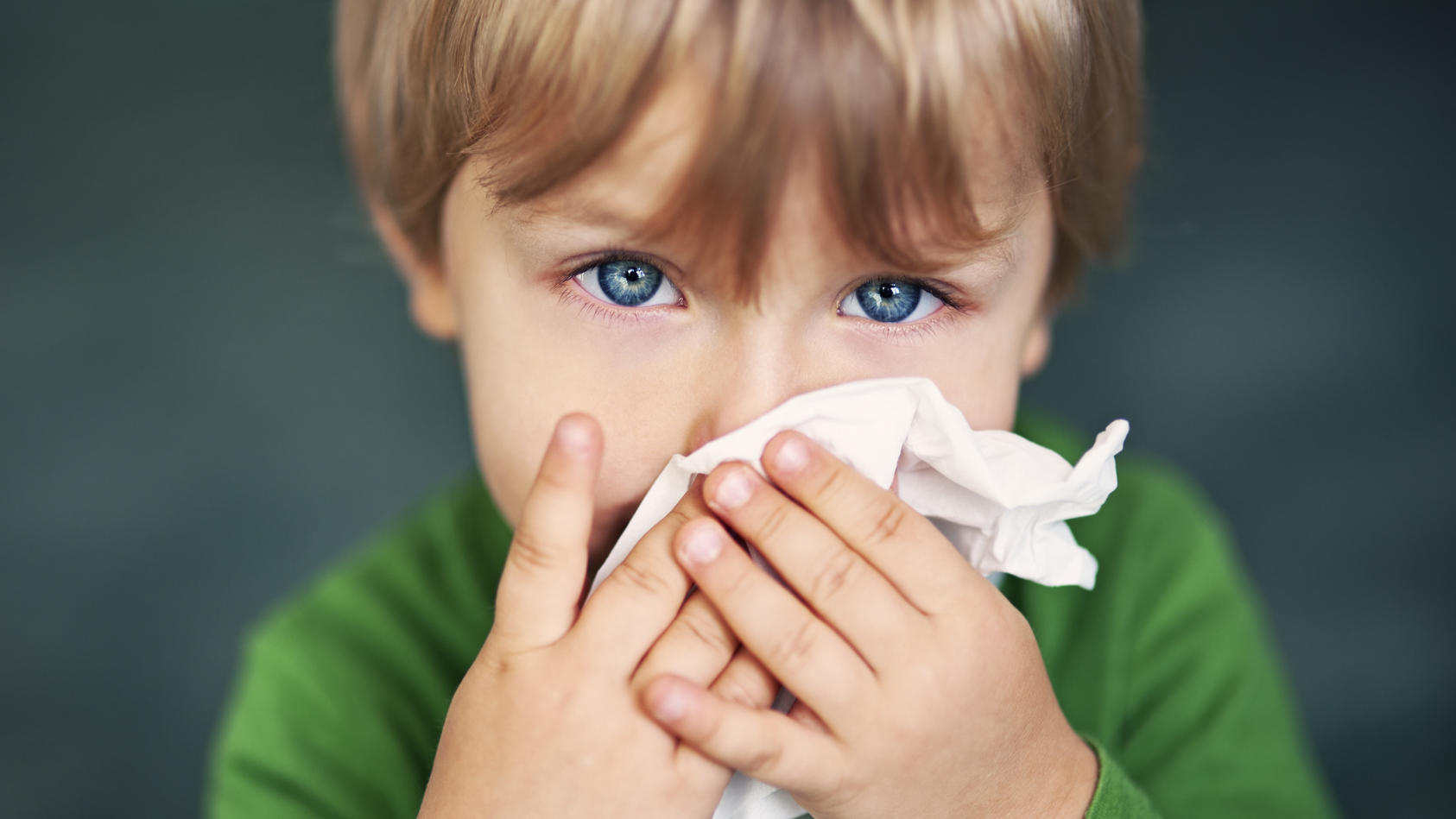 Erkälteter Junge putzt sich die Nase mit einem Taschentuch