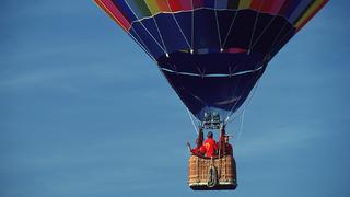 Ein Heißluftballon in der Luft mit einem blauen Himmel als Hintergrund.