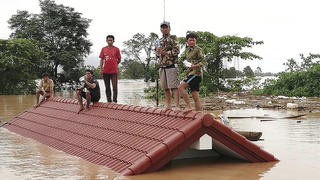 24.07.2018, Laos, Attapeu: Dorfbewohner haben sich vor den Wassermassen aus einem eingestürzten Staudamm auf die Dächer eines Hauses gerettet. Nach dem Bruch des Damms Xepian-Xe Nam Noy sind Tausende Häuser und Wohnungen weggespült worden, Hunderte Menschen werden vermisst. Foto: -/Attapeu Today/AP/dpa +++ dpa-Bildfunk +++