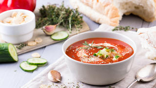 fresh tomato soup in a grey bowl. Traditional spanish soup gazpacho with herbs, little croutons, pepper and fresh cucumbers.