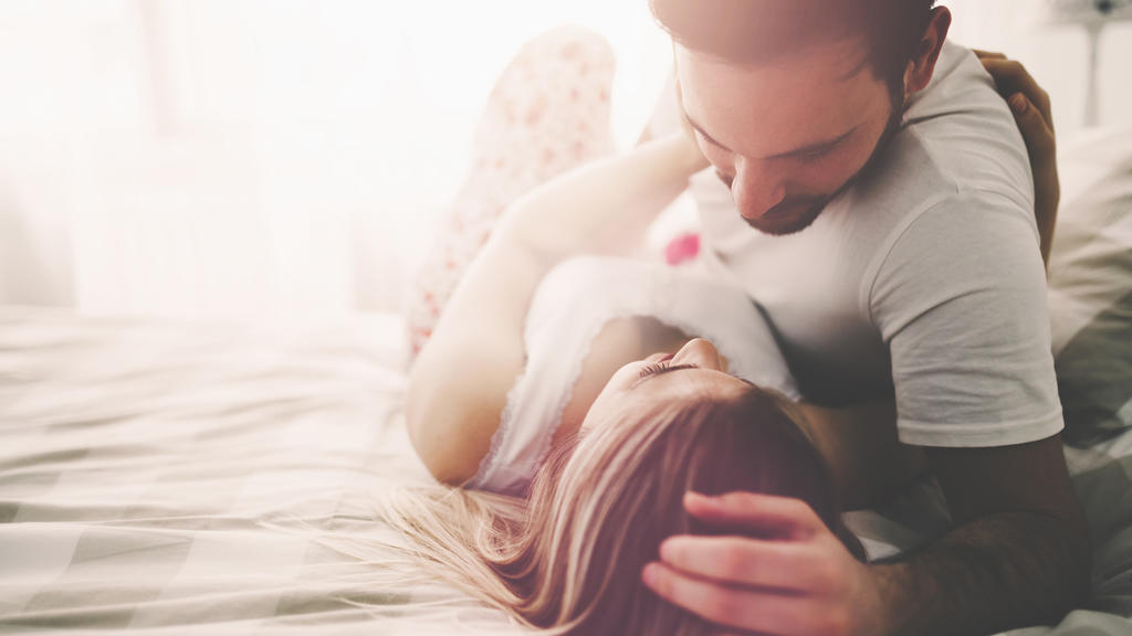 Sensual romantic foreplay by couple in love in bed