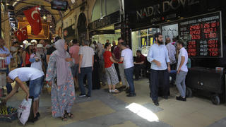 13.08.2018, Türkei, Istanbul: Menschen gehen an einer Wechselstube vorbei. Nach einem weiteren dramatischen Absacken der Lira an den Börsen haben der Finanzminister und die Zentralbank am 13.08. Notfallmaßnahmen ergriffen. Foto: Mucahid Yapici/AP/dpa +++ dpa-Bildfunk +++
