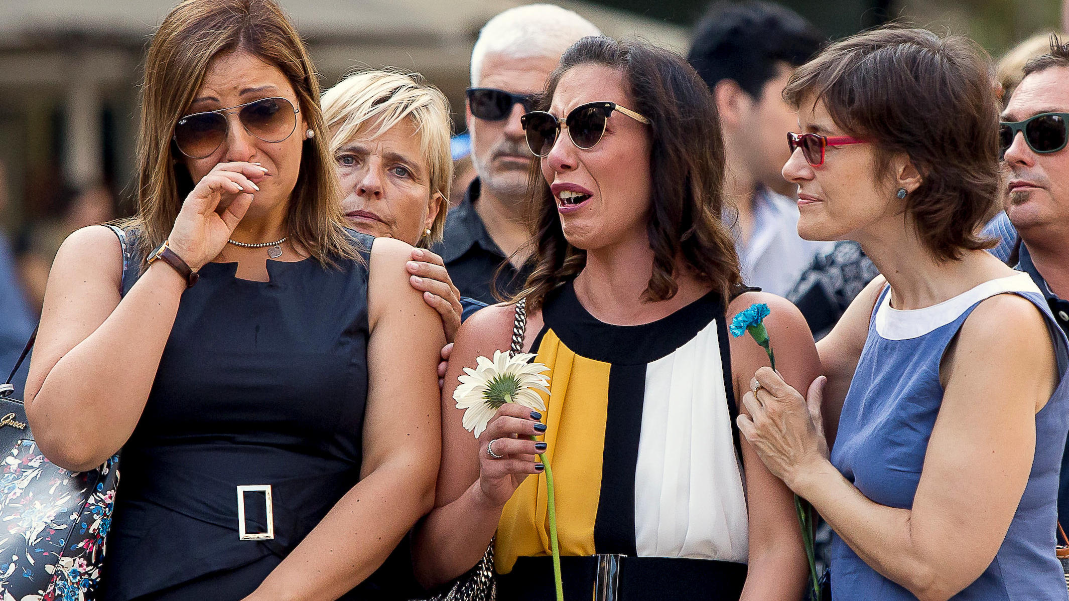 Relatives react before placing flowers in memory of victims of the twin Islamist attacks on the Catalan capital and the coastal town of Cambrils that killed 16 people, during a ceremony to mark the first anniversary of the attacks at Las Ramblas, cen