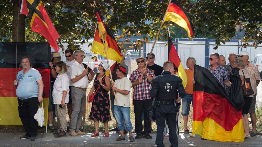 ARCHIV - 16.08.2018, Sachsen, Dresden: Teilnehmer einer Demonstration der islamfeindlichen Pegida-Bewegung stehen anlässlich des bevorstehenden Besuchs von Bundeskanzlerin Merkel (CDU) im Sächsischen Landtag an einer Straßenkreuzung. Bundesjustizmini
