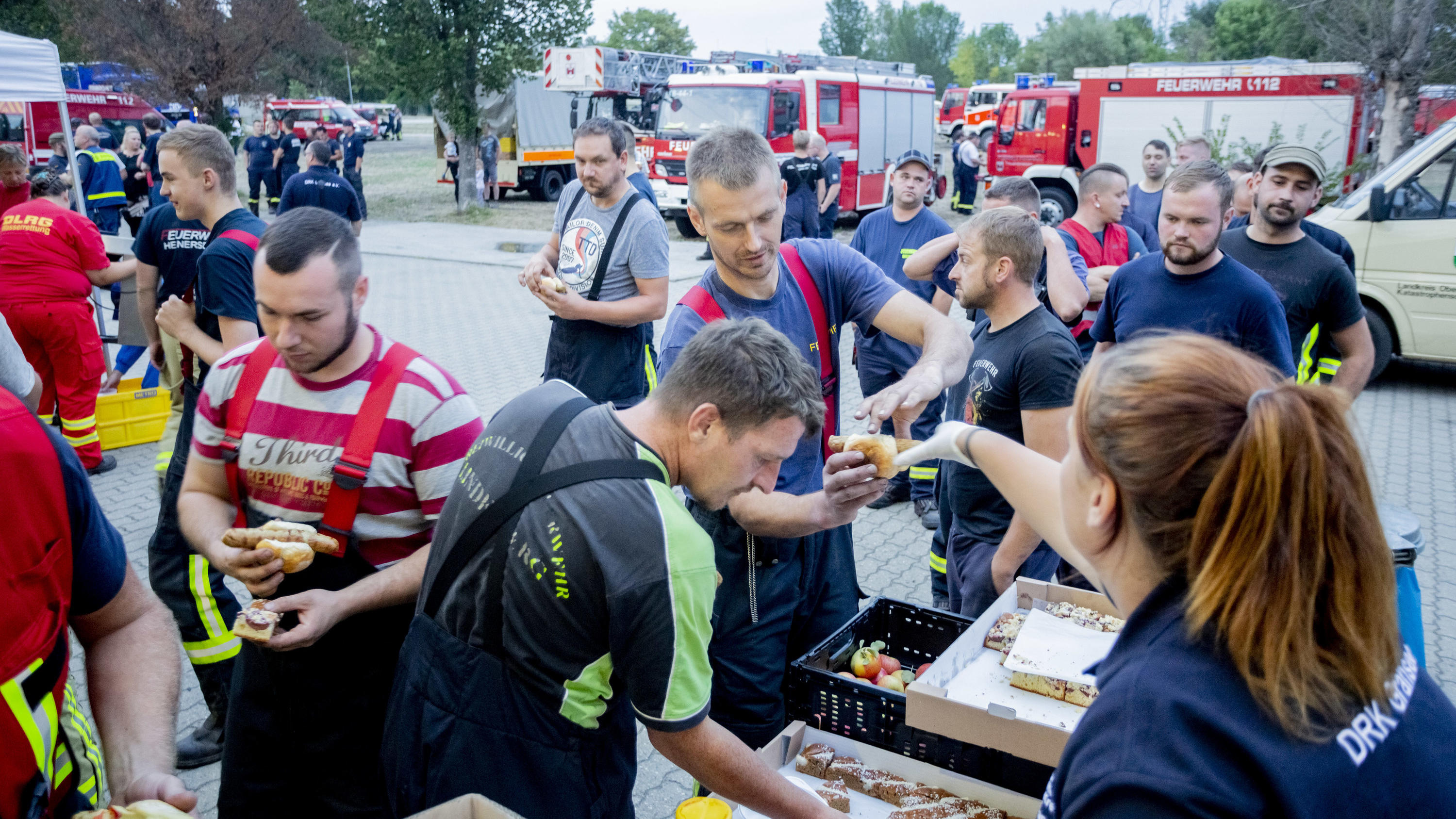 24.08.2018, Brandenburg, Treuenbrietzen: Einsatzkräfte holen sich bei der Feuerwache Treuenbrietzen an einer mobilen Küche Stärkung. Foto: Christoph Soeder/dpa +++ dpa-Bildfunk +++