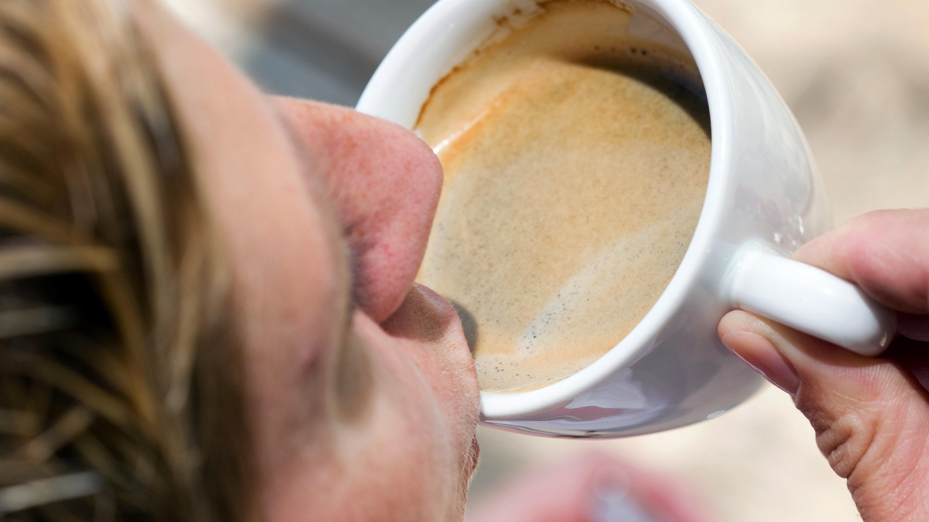 Eine Frau trinkt eine Tasse Kaffee-Crema. dpa