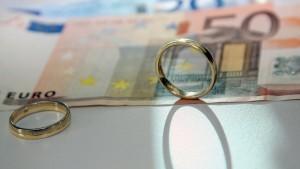  Zwei Eheringe liegen auf Geldscheinen