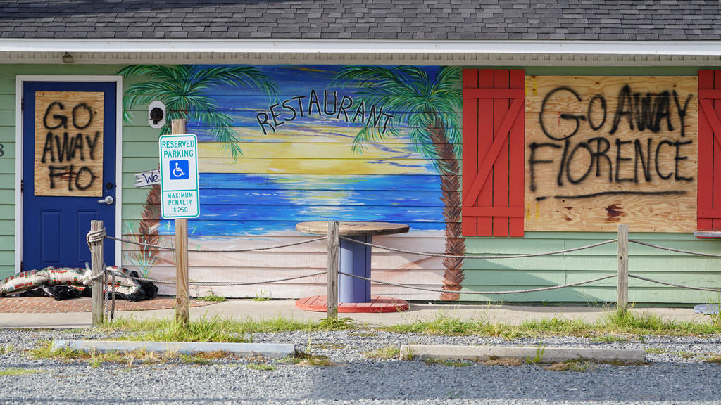 A sign is posted on a boarded up building before Hurricane Florence comes ashore on Oak Island, North Carolina, U.S., September 12, 2018. REUTERS/Carlo Allegri