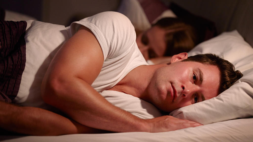 Man Lying Awake In Bed Suffering With Insomnia
