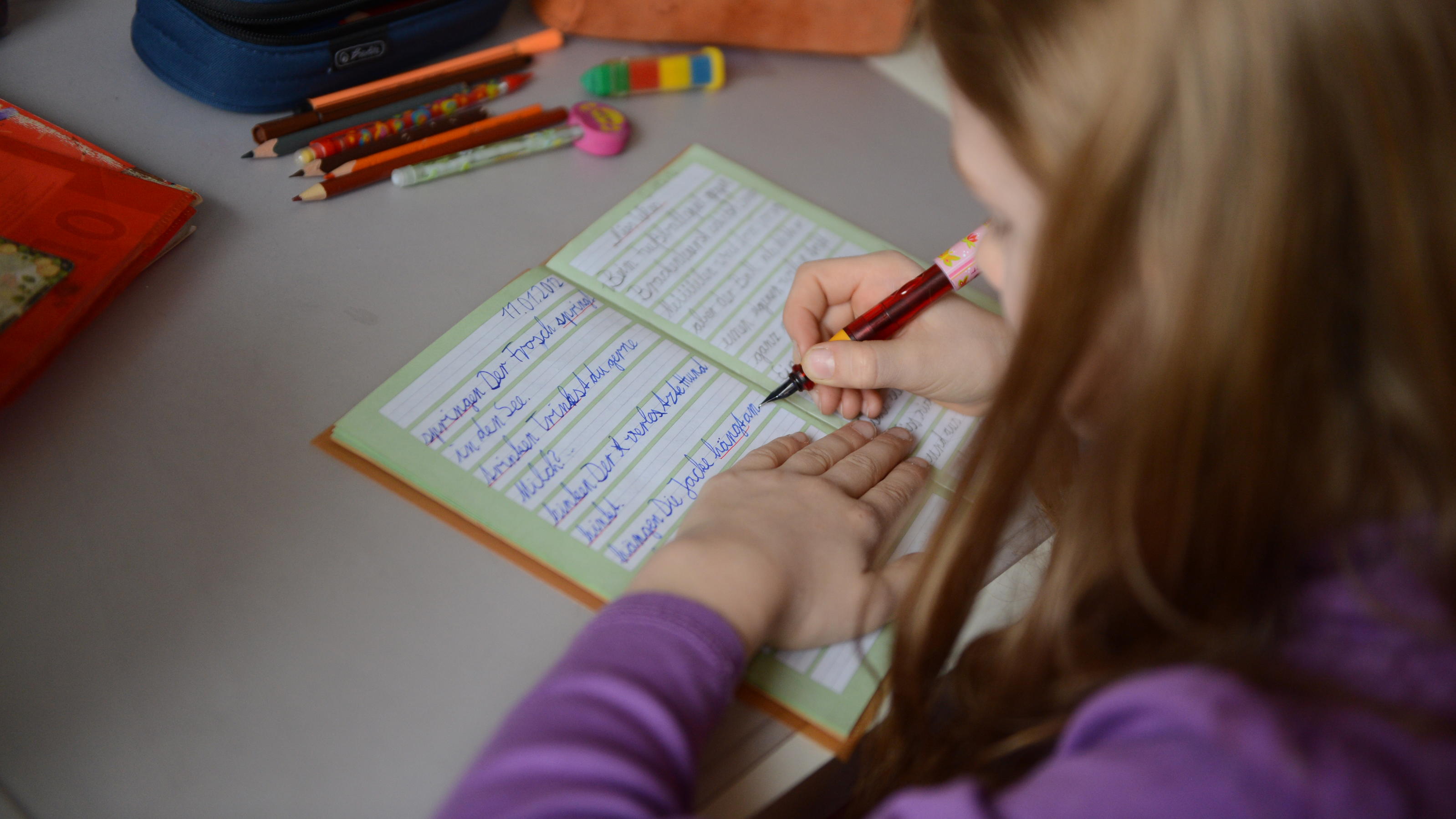 Illustration - Ein achtjähriges Mädchen übt in ihrem Schreibheft die deutsche Rechtschreibung, aufgenommen am 10.4.2012 in Berlin. Foto: Jens Kalaene