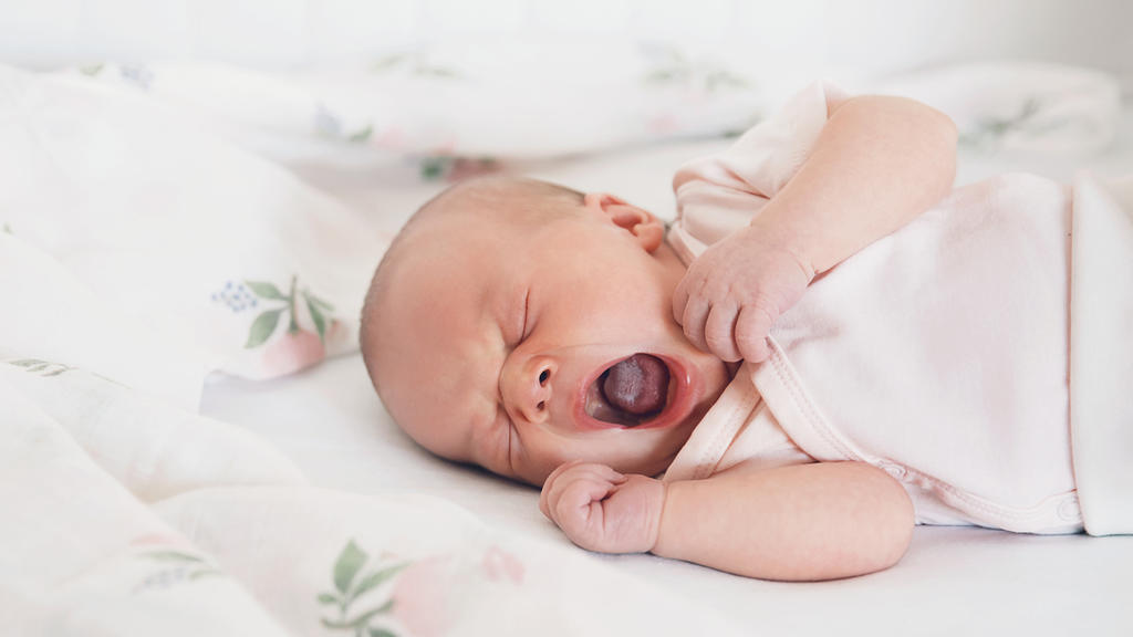 Neugeborenes Baby gähnt und hat eine weißliche Zunge, ein Zeichen für Mundsoor