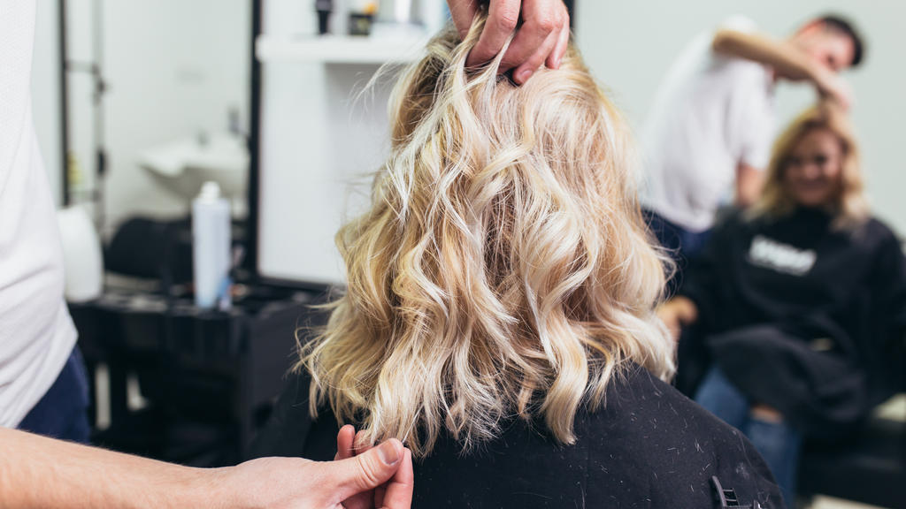 Friseur stylt Haare von Frau.