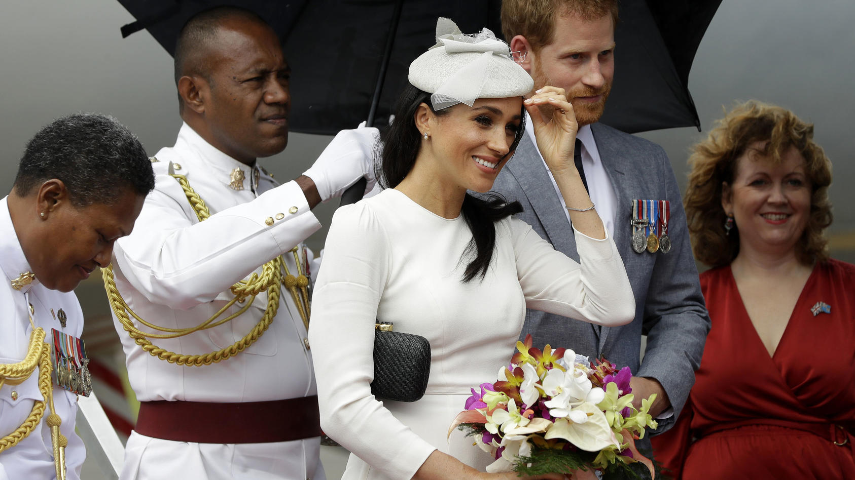 23.10.2018, Fidschi, Suva: Der britische Prinz Harry, Herzog von Sussex, und seine Frau Meghan (M), Herzogin von Sussex, nach ihrer Ankunft aus dem Flughafen. Foto: Kirsty Wigglesworth/Press Association/dpa +++ dpa-Bildfunk +++