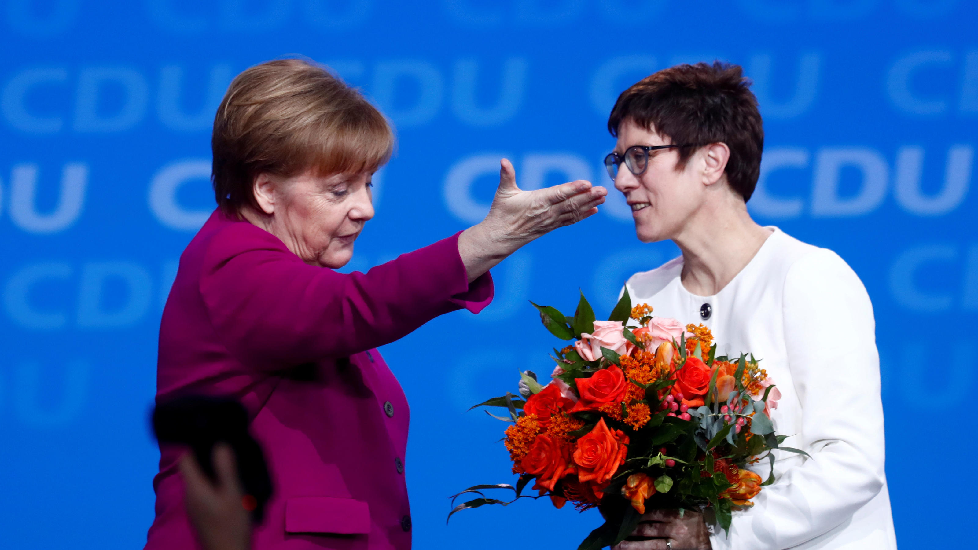 FILE PHOTO: German Chancellor Angela Merkel gestures beside Annegret Kramp-Karrenbauer after she was elected secretary general during a Christian Democratic Union (CDU) party congress in Berlin, Germany, February 26, 2018.    REUTERS/Hannibal Hanschk
