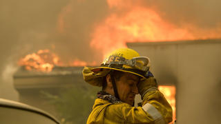 dpatopbilder - 09.11.2018, USA, Malibu: Ein Feuerwehrmann ist im Einsatz, während ein Haus in der Nähe des Malibou Lake brennt. Bei den Waldbränden in Kalifornien sind mindestens fünf Menschen ums Leben gekommen. Foto: Ringo H.W. Chiu/AP/dpa +++ dpa-Bildfunk +++