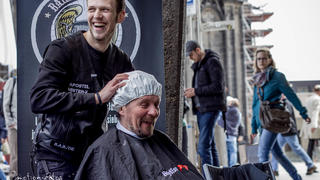 Der "Barber Angel" wäscht die Haare des obdachlosen Menschen unter der Waschhaube.