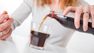 Frau gießt sich Cola in ein Glas