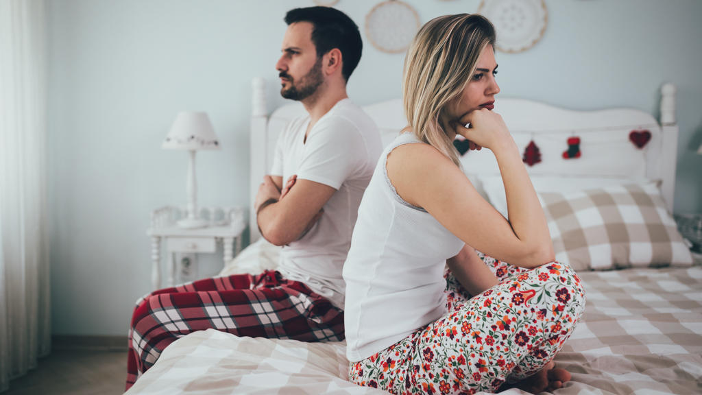 Paar sitzt gelangweilt im Bett