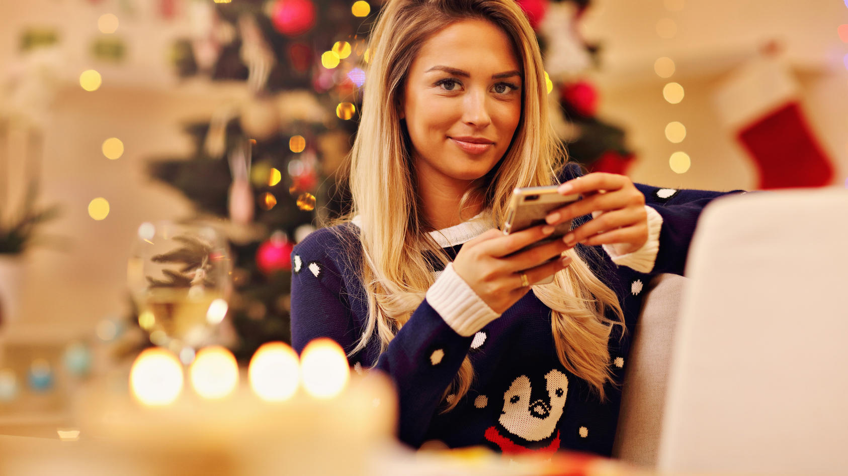Frau mit Smartphone in weihnachtlich geschmückter Wohnung