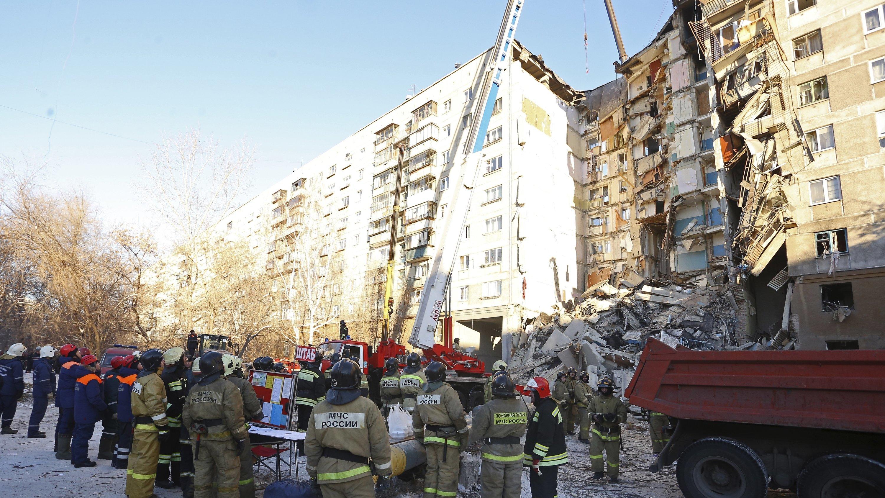 31.12.2018, Russland, Magnitogorsk: Rettungskräfte stehen vor einem Wohnhaus, das durch eine Gasexplosion beschädigt worden ist. Bis zum Montagmittag (Ortszeit) sprachen die Behörden von mindestens vier Toten. Zehn Menschen seien verletzt gerettet wo