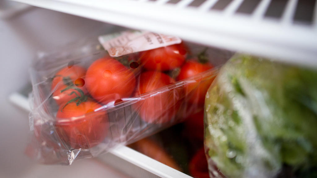 Eine Plastikverpackung mit Tomaten liegt im Kühlschrank.