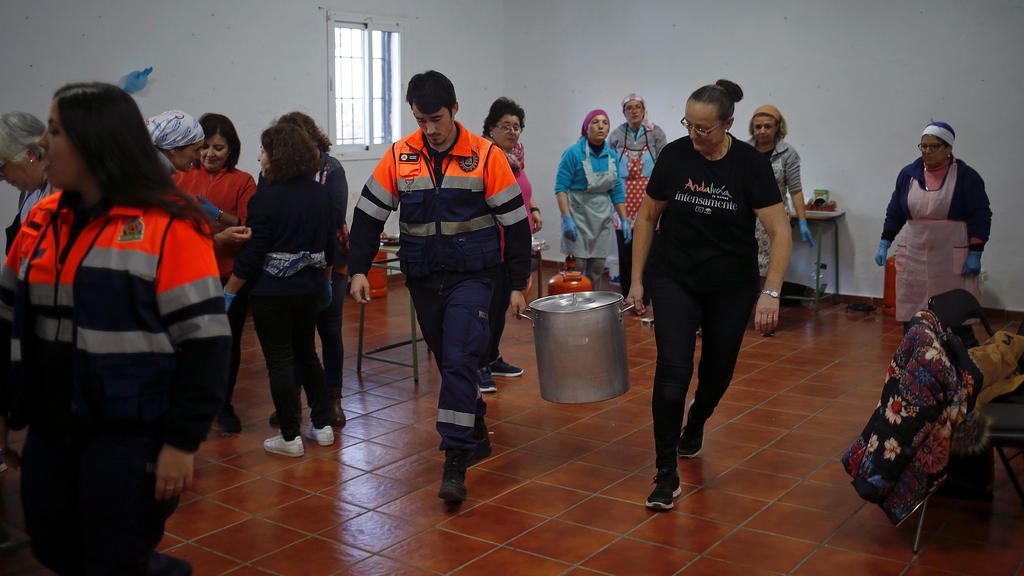 A member of Civil Protection and a volunteer carry a pot with food for the rescue personnel at the area where Julen, a Spanish two-year-old boy, fell into a deep well eight days ago when the family was taking a stroll through a private estate, in Tot