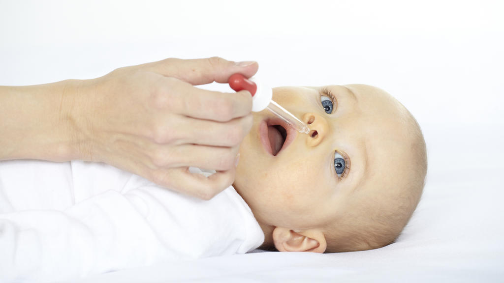 Baby hat Schnupfen und bekommt Nasentropfen.