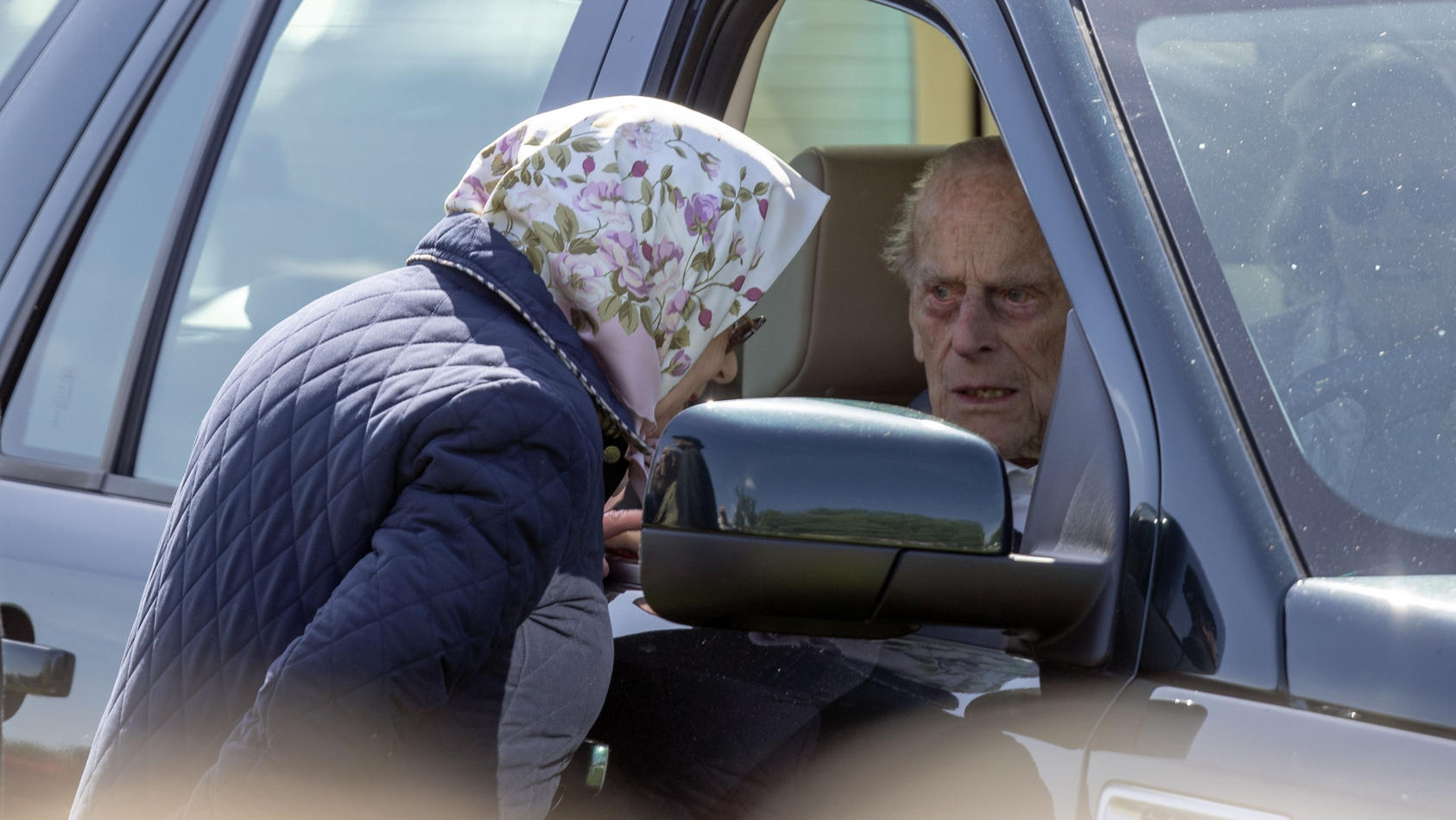 ARCHIV - 11.05.2018, Großbritannien, Windsor: Die britische Königin Elizabeth II. spricht mit ihrem Ehemann Prinz Philip, Herzog von Edinburgh, der am Rande der Pferdeschau «Royal Windsor Horse Show» am Schloss Windsor am Steuer seines Fahrzeuges sit