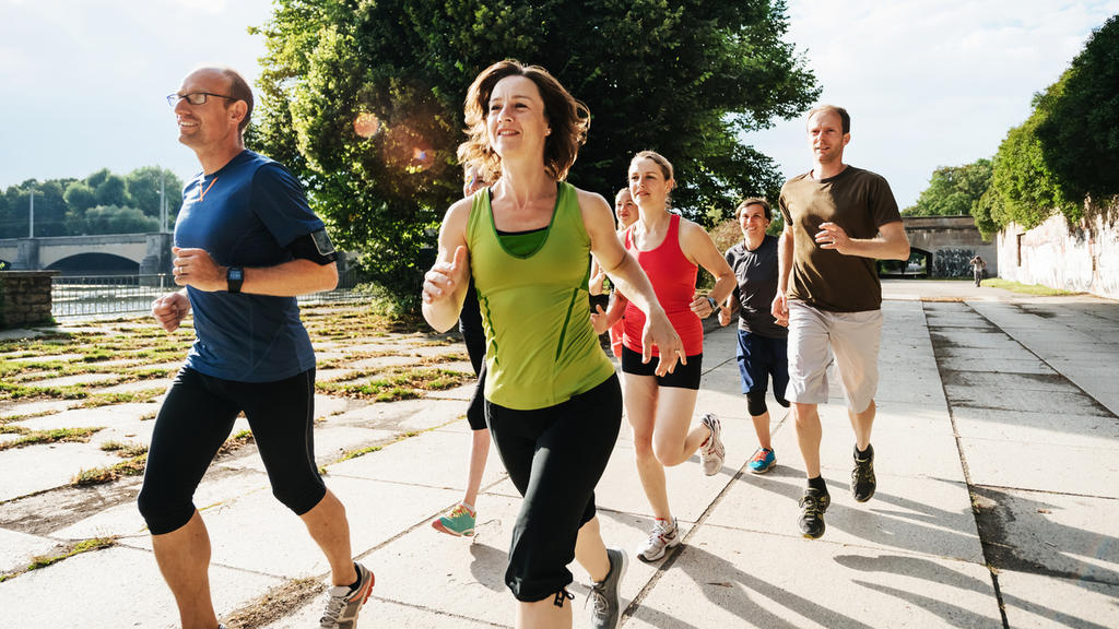 A group of amateur athletes out for a jog in the city, training together in the afternoon sun.