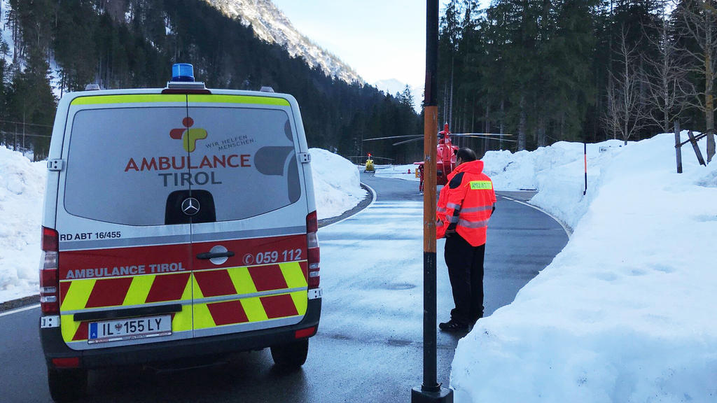 23.02.2019, Österreich, Innsbruck: Ein Krankenwagen und zwei Hubschrauber blockieren die Straße. Bei einem Lawinenabgang unweit der deutsch-österreichischen Grenze sind nach Polizeiangaben mindestens zwei Menschen verschüttet worden. Foto: Zeitungsfo