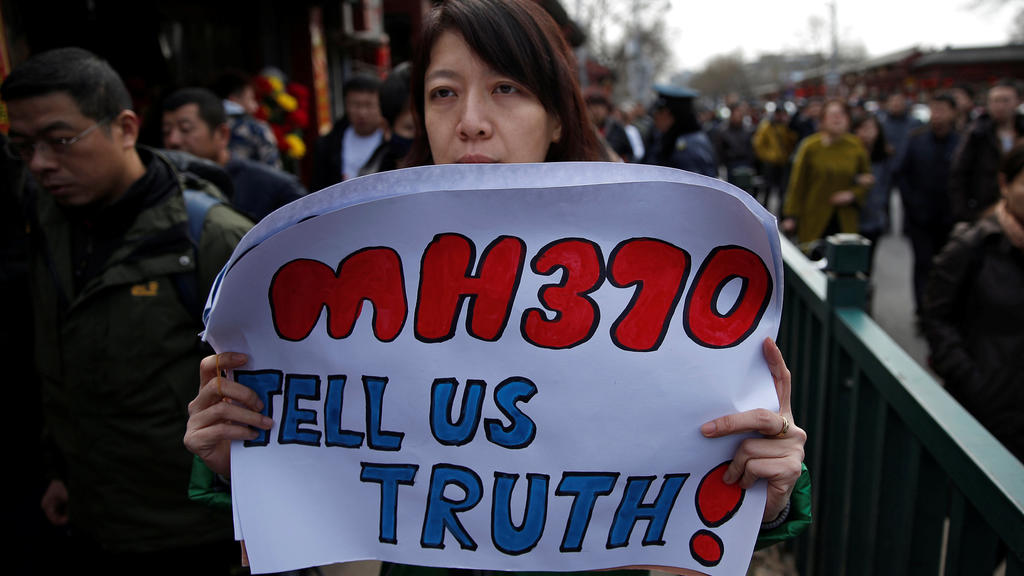 FILE PHOTO: Catherine Gang, whose husband Li Zhi was onboard the missing Malaysia Airlines flight MH370, holds a banner as she walks outside Yonghegong Lama Temple after a gathering of family members of the missing passengers in Beijing March 8, 2015