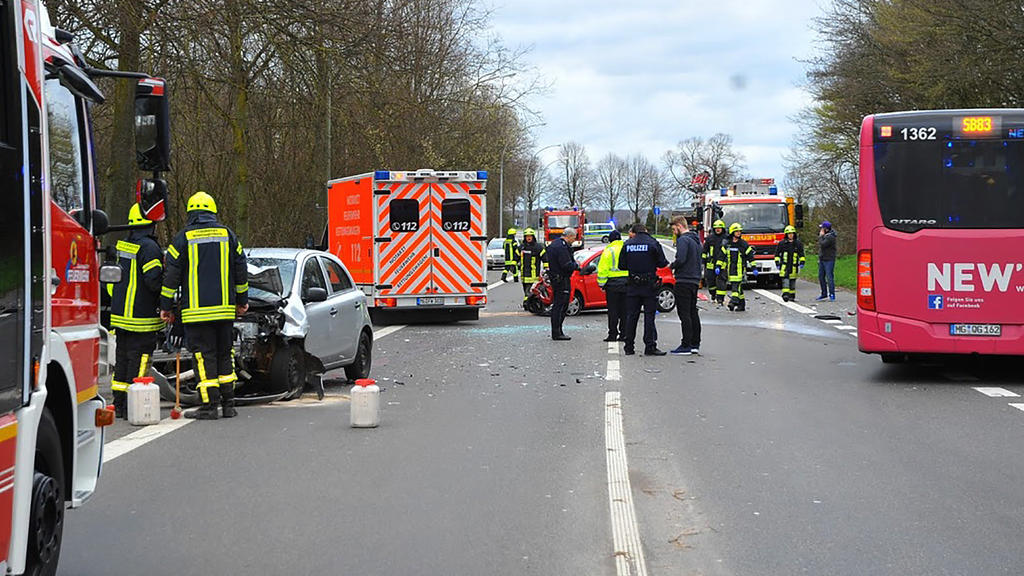 16.03.2019, Nordrhein-Westfalen, Mönchengladbach: Polizisten und Einsatzkräfte stehen an einer Unfallstelle neben einem stark beschädigtem PKW und einem Bus. Bei dem Unfall, bei dem ein Linienbus und ein Auto ineinander gefahren waren, sind mindesten