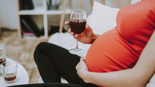 Schwangere Frau trinkt einen Wein.