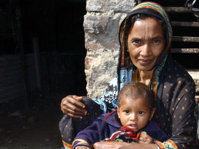 Mit ihrem Kind auf dem Arm sitzt eine obdachlose Frau am Mittwoch (02.02.2005) in einem Slum am Rande der indischen Millioeenstadt Neu Delhi unter einer Brücke. Während in den Innenstädten moderne Business-Districts entstehen, leben zahllose der mehr