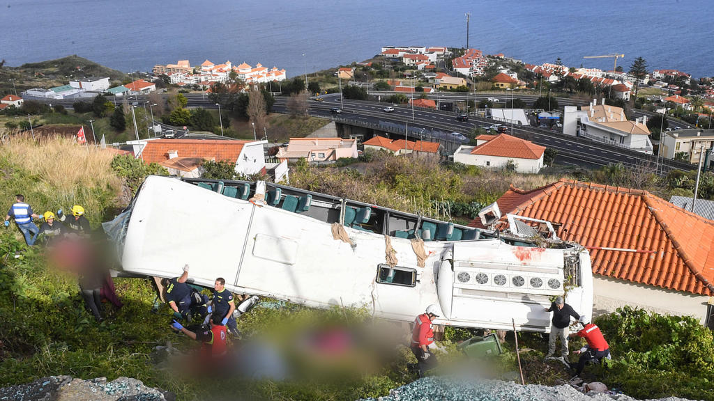 17.04.2019, Portugal, Canico: Rettungskräfte stehen nach einem schweren Busunglück auf der portugiesischen Ferieninsel Madeira an dem Bus. Bei dem Busunglück auf der portugiesischen Atlantikinsel Madeira sind 29 Menschen ums Leben gekommen. Unter den