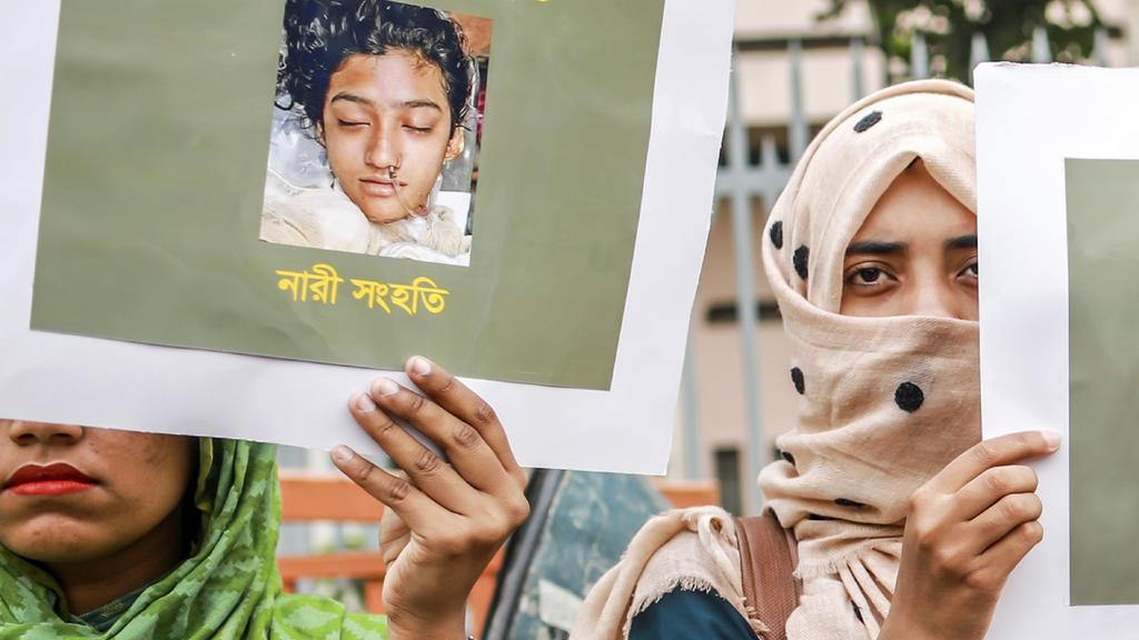 In this photo taken on April 12, 2019 Bangladeshi women hold placards and photographs of schoolgirl Nusrat Jahan Rafi at a protest in Dhaka, following her murder by being set on fire after she had reported a sexual assault. - A schoolgirl was burned 