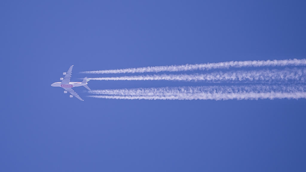 Kondensstreifen eines Flugzeugs der Fluggesellschaft Qatar Airways sind am blauen Himmel zu sehen.