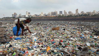 ARCHIV - 04.06.2018, Indien, Mumbai: Ein Mann sammelt Plastik und andere wiederverwertbare Materialen an der von Plastiktüten und sonstigen Müll übersäten Küste des Arabisches Meeres.   (zu dpa "Bundesregierung will Exportverbot für unsortierten Plastikmüll") Foto: Rafiq Maqbool/AP/dpa +++ dpa-Bildfunk +++