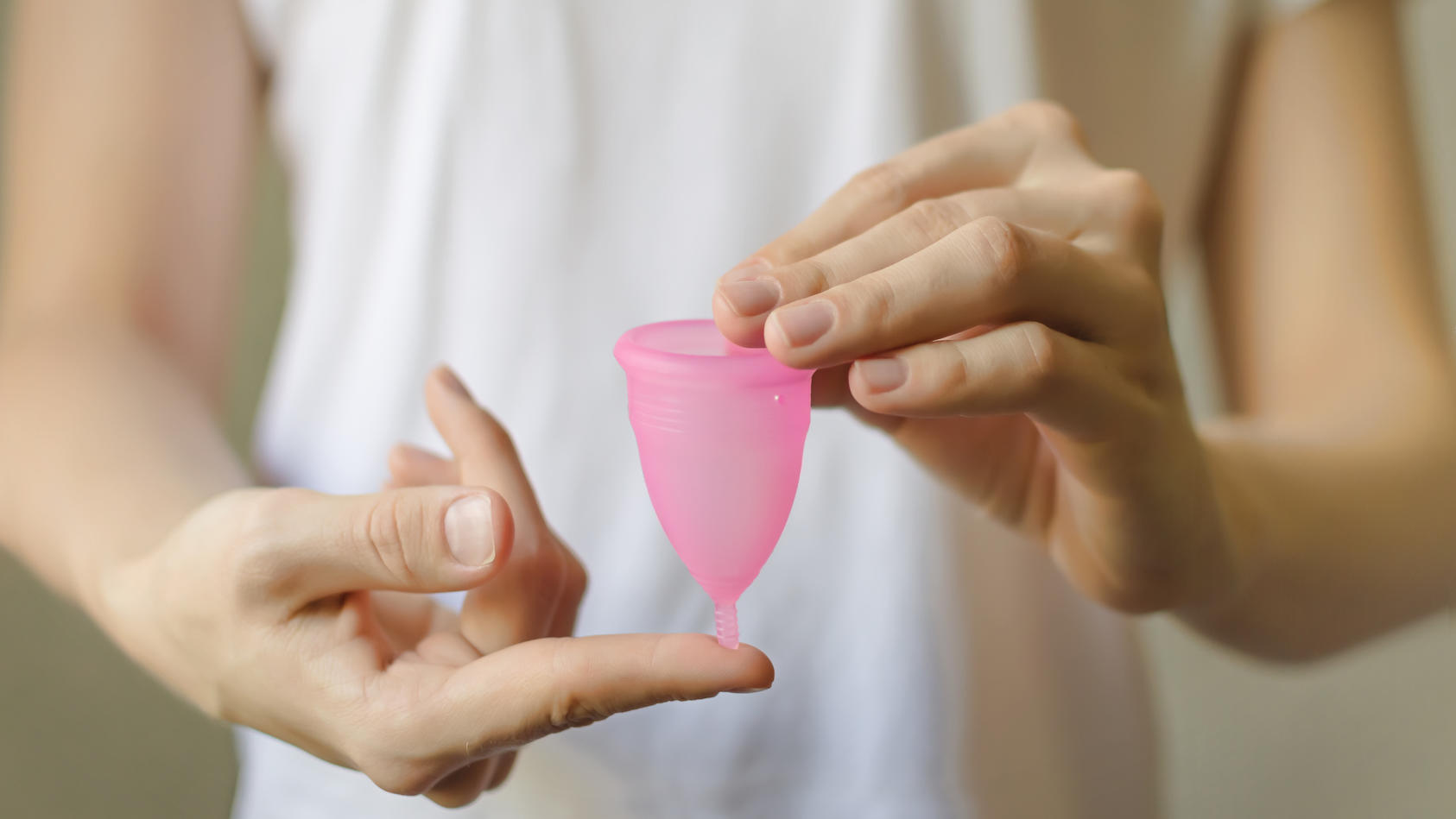Frau hält Menstruationstasse in der Hand.