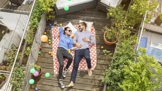 Young couple relaxing on their balcony, lying on blanket with arms around model released Symbolfoto property released PUBLICATIONxINxGERxSUIxAUTxHUNxONLY PESF01171  