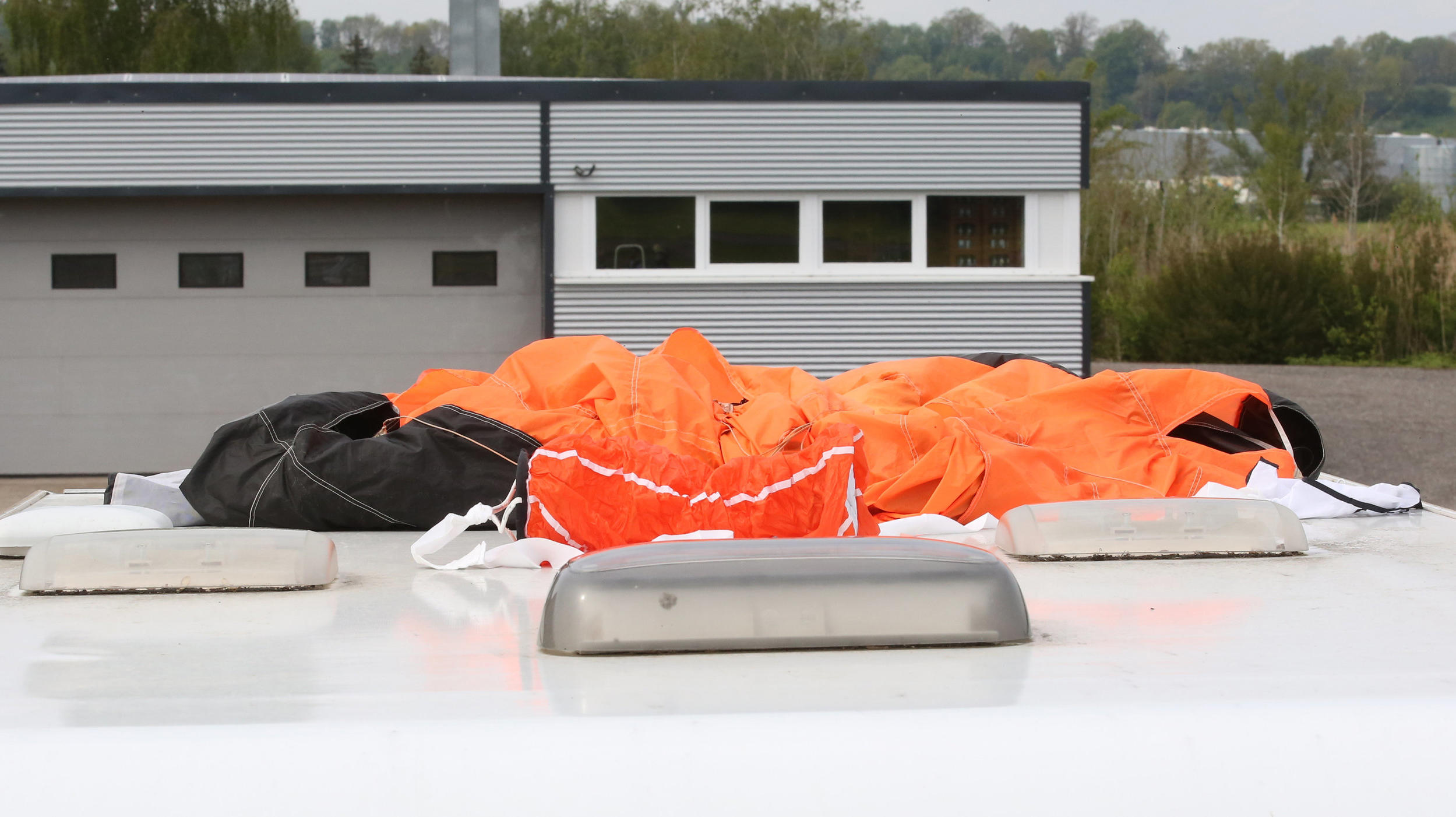 18.05.2019, Baden-Württemberg, Bad Saulgau: Der Fallschirm eines der Verunglückten, so die Einsatzkräfte, liegt auf dem Dach eines Wohnmobiles auf dem Parkplatz am Flugplatz. Am Morgen sind dort zwei Fallschirmspringer bei einem Sprung tödlich verlet