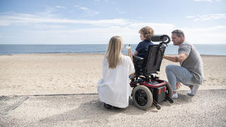 Behindertes Kind mit Eltern am Strand