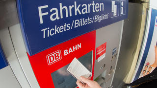 ARCHIV - 30.01.2014, Bayern, Straubing: ILLUSTRATION - Ein Fahrgast hält ein Ticket vor einen Fahrkartenautomaten der Deutschen Bahn. Die Deutsche Bahn schafft das Schöne-Wochenende-Ticket ab. Foto: Armin Weigel/dpa +++ dpa-Bildfunk +++