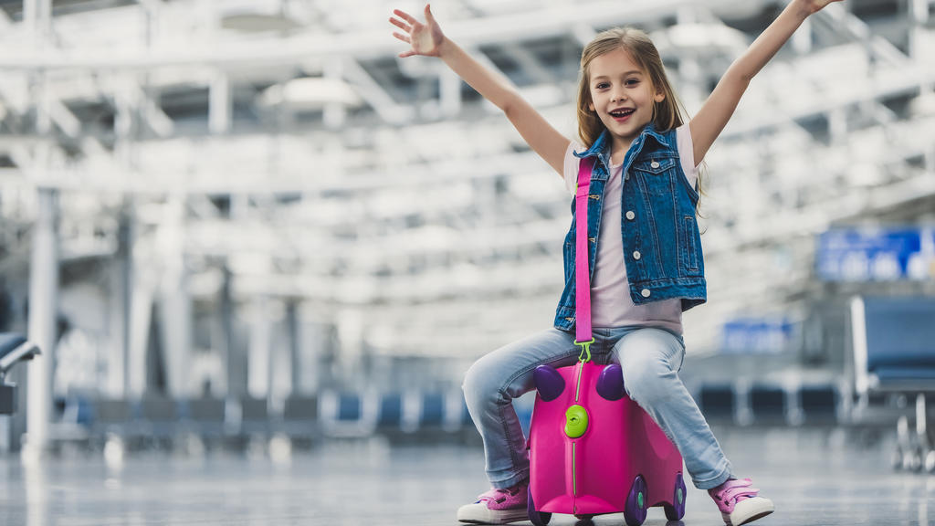 Das Gepäck ist aufgegeben und das kleine Mädchen ist bereit, mit seinem Handgepäck, den Flieger zu besteigen