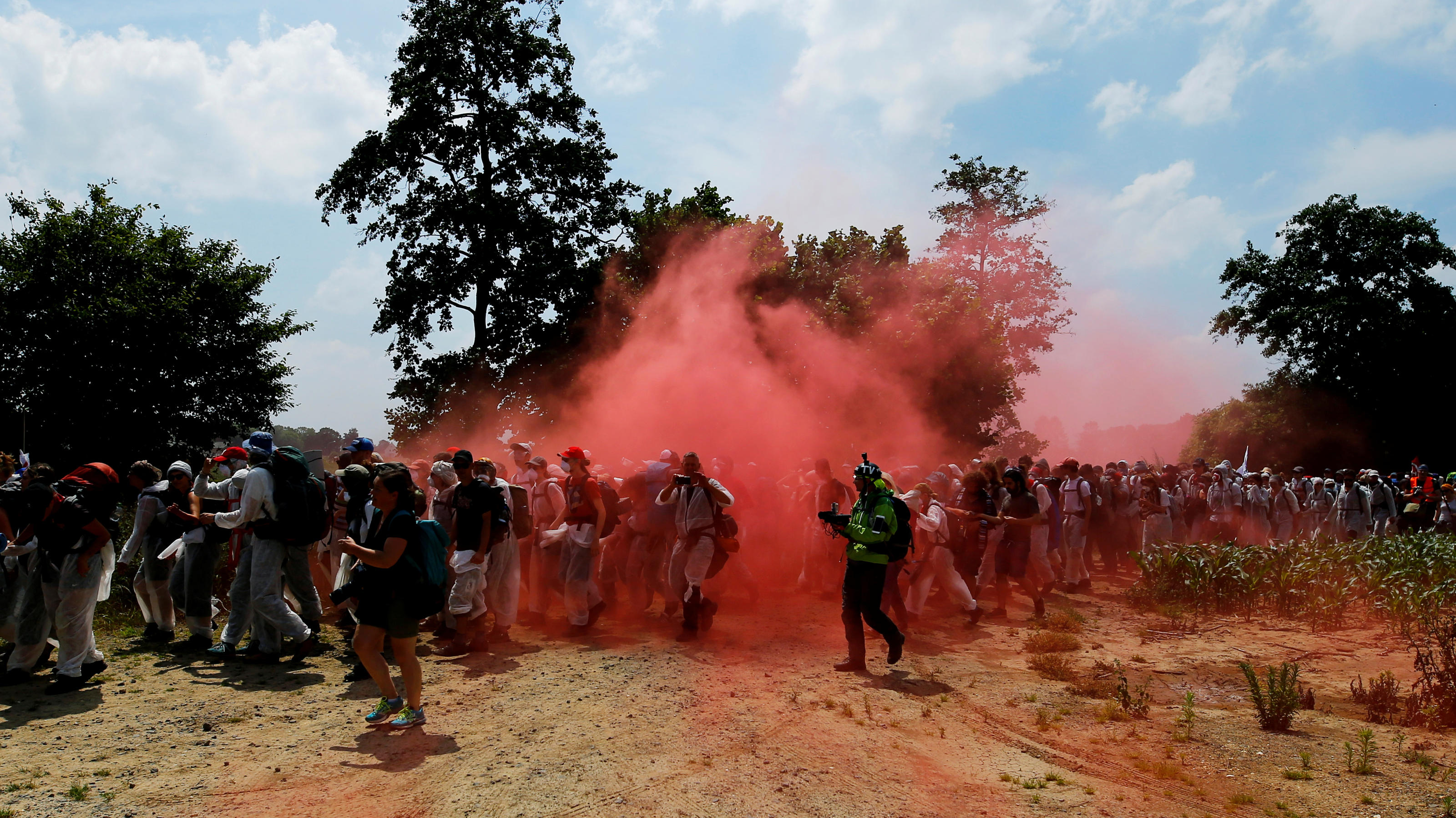 Environmental activists walk amid the red smoke from flares during a protest against the climate change near a pit of Garzweiler open cast brown coal mine near Duesseldorf, Germany June 22, 2019. REUTERS/Thilo Schmuelgen