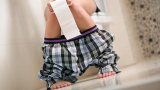 Frau sitzt mit Durchfall auf der Toilette