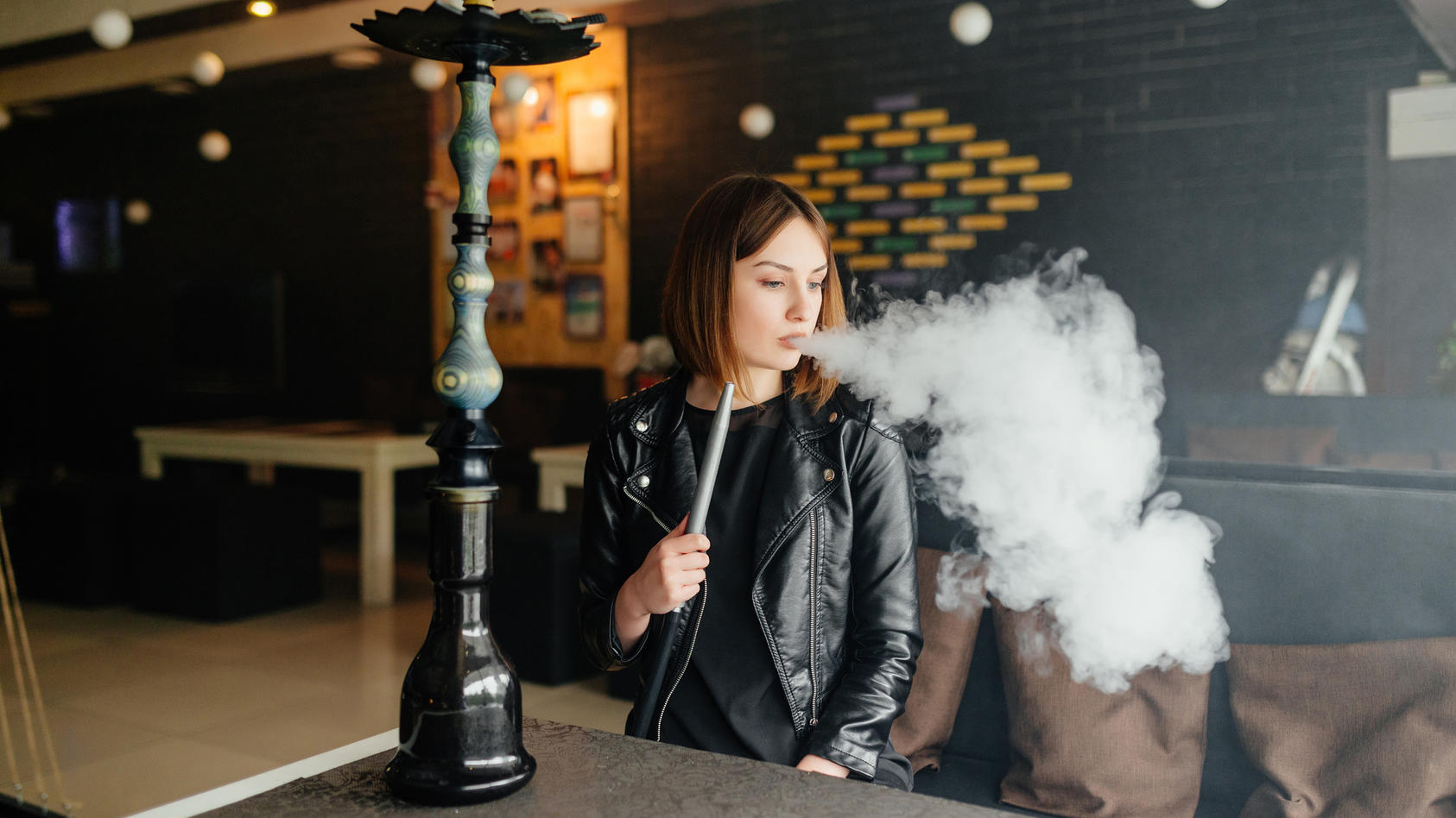 Junge Frau in einer Bar raucht Shisha