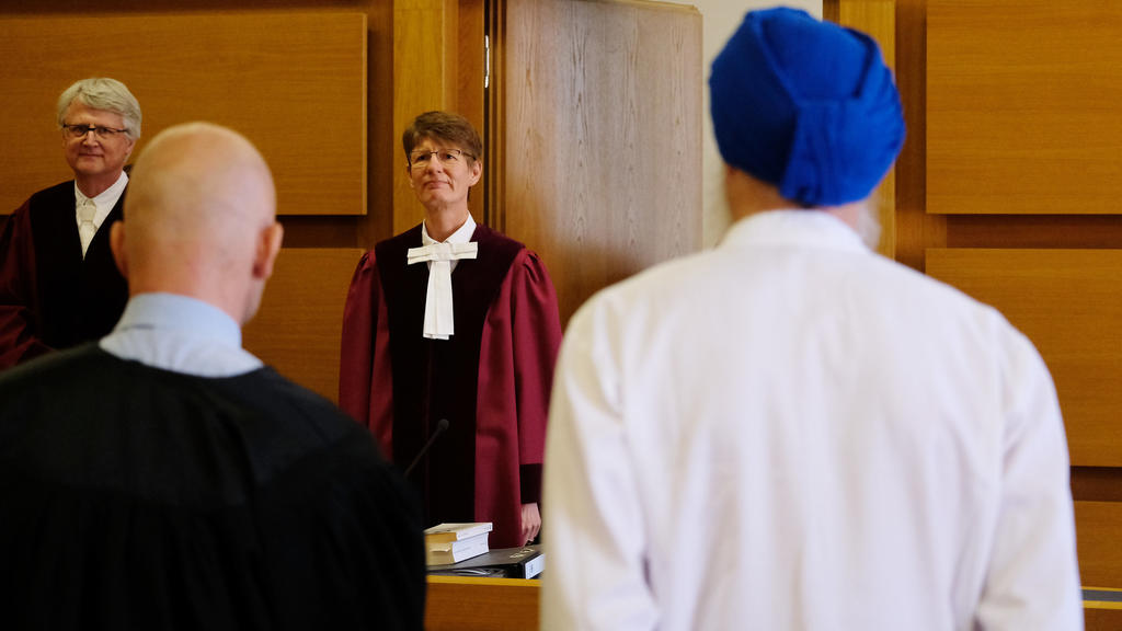 04.07.2019, Sachsen, Leipzig: Renate Philipp (M), Vorsitzende Richterin am Bundesverwaltungsgericht, steht in einem Verhandlungssaal. Ein Turban tragender Sikh (r) klagt, weil er aus religiösen Gründen von der Helmpflicht auf dem Motorrad befreit wer