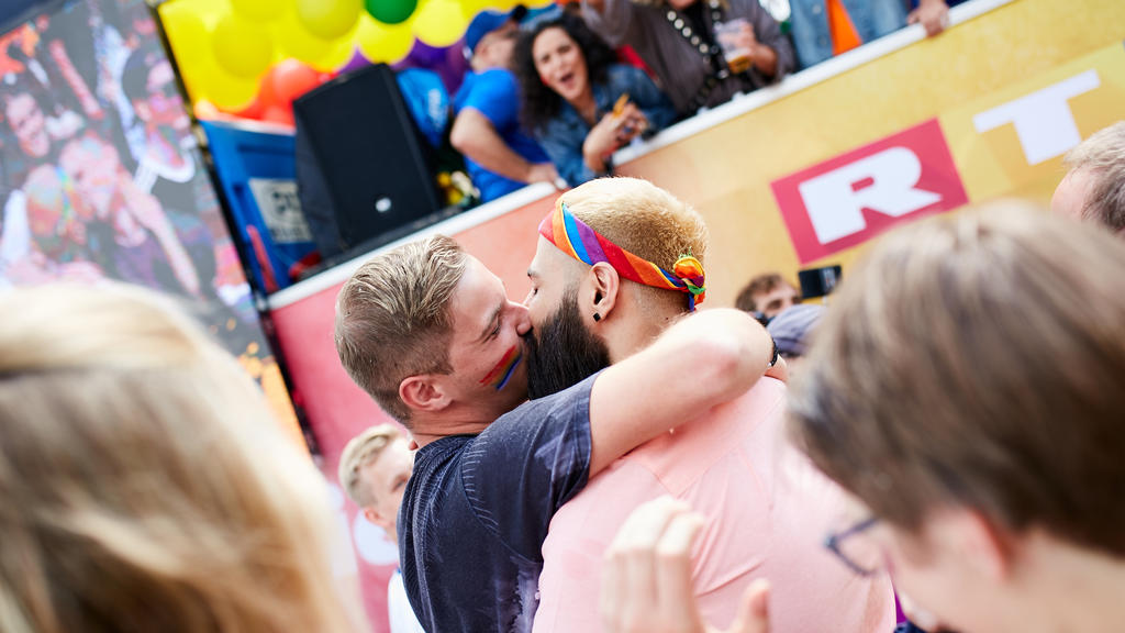 Schwules Paar küsst sich vor dem RTL-Wagen.